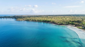 An aerial view of a coastal area with clear turquoise waters, a sandy beach, and a densely forested peninsula. - Veranda Tamarin Hotel & Spa (Tamarin)