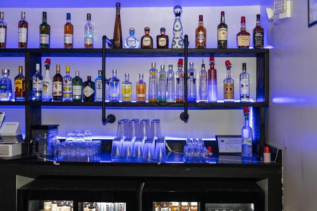 A bar area with multiple shelves of liquor bottles and glasses.