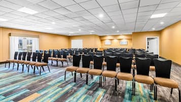 A conference room with rows of chairs, a patterned carpet, and a ceiling with recessed lighting.