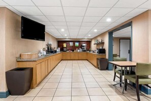 Un área de cocina moderna con un televisor de pantalla plana, una cafetera y un cubo de basura.