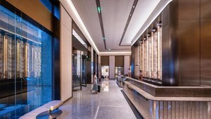 Un moderno vestíbulo de hotel con mostrador de recepción, zona de estar y paredes de vidrio.