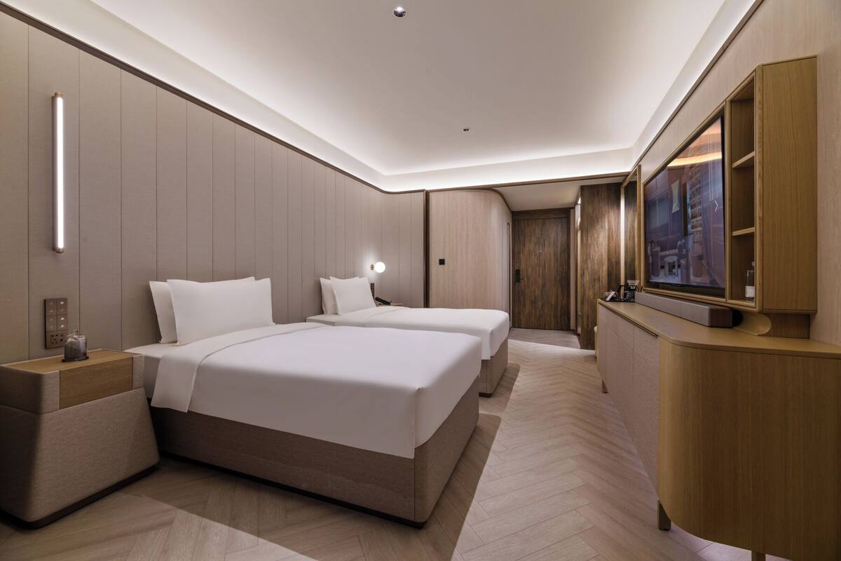 Una habitación de hotel moderna con una cama grande, mesitas de noche, un televisor y un armario de madera.