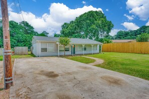 A single-story house with a front yard, a wooden fence, and a clear sky.