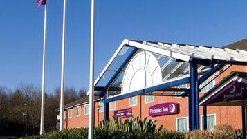 A hotel with a glass facade, a sign for Premier Inn, and three flags.