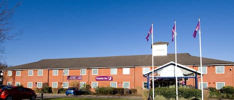 A brick building with a sign for Premier Inn, a covered entrance, and flags.