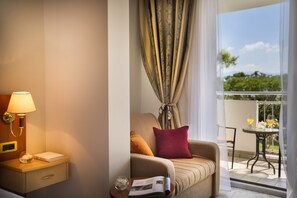 A hotel room with a bed, a nightstand with a lamp, a window with curtains, and a view of the outdoors. - Sunny Baška Residence (Baska)