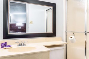 A bathroom with a large mirror, a sink, and a shower. - Knights Inn Searcy (Searcy)