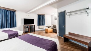 A hotel room with two beds, a TV, a desk, a chair, a bench, and a coat rack. - Knights Inn Searcy (Searcy)
