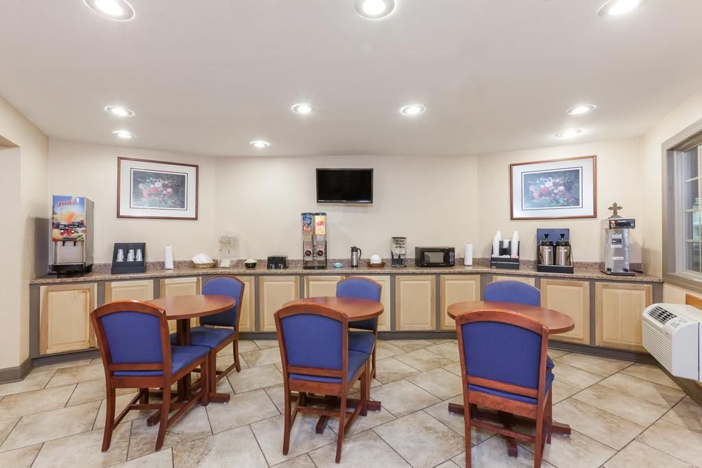 Une chambre d’hôtel équipée d’une kitchenette, d’un téléviseur à écran plat, d’œuvres d’art encadrées et d’un coin salon avec des fauteuils.