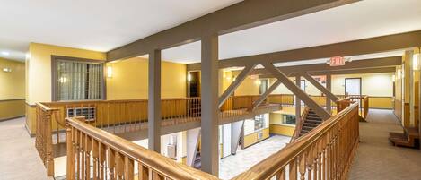 A multi-level interior with wooden railings, a staircase, and an exit sign.