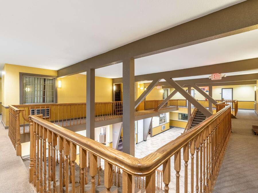 A multi-level interior with wooden railings, a staircase, and an exit sign.