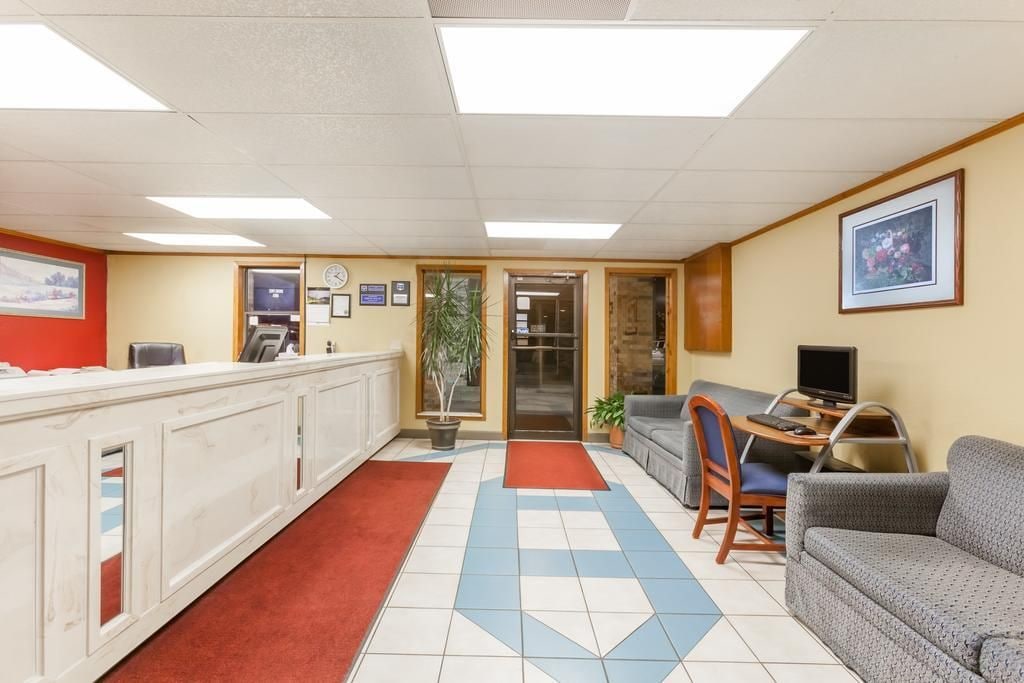 A reception area with a counter, a seating area with a sofa and chairs, a television, and a plant.