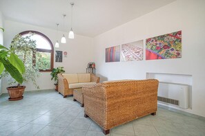 A living room with wicker furniture, a fireplace, and wall art. - Hotel la Baja (Cuglieri)