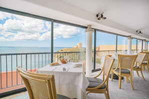 Ein Balkon mit Esstisch, mit Blick auf ein Gewässer und ein entferntes Gebäude.