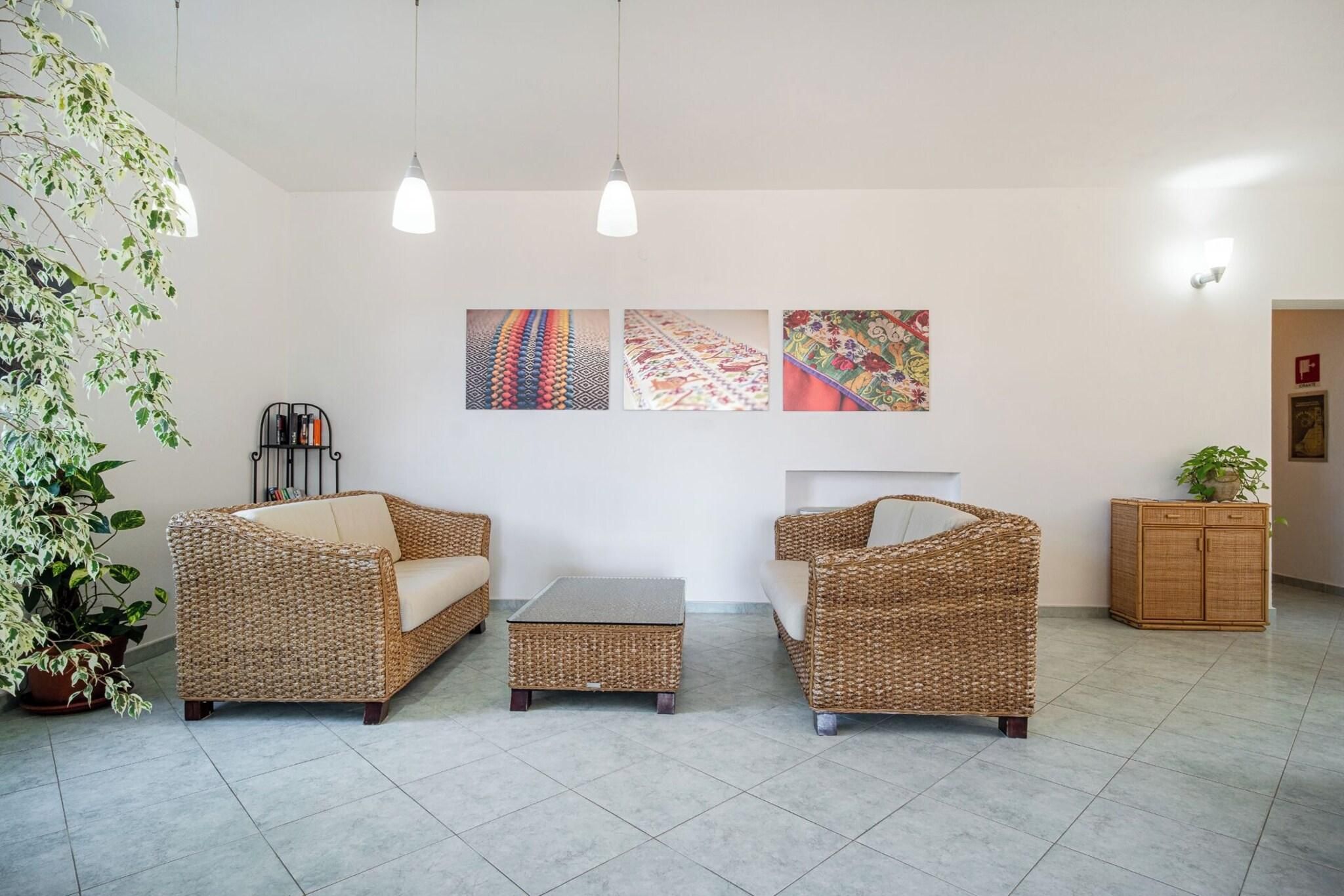 Ein Zimmer mit Korbmöbeln, Fliesenboden und Wandbildern.