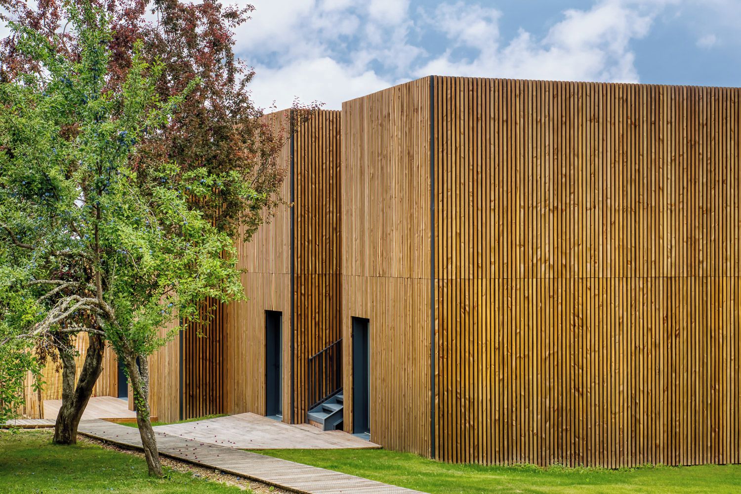 Un edificio moderno con paneles verticales de madera y una escalera que lleva a una entrada.