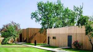 A modern building with a wooden facade, a small entrance, and a pathway leading to a grassy area with trees. - Hotel Le Domaine De Baulieu (Auch)