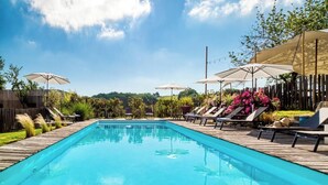 A rectangular swimming pool with lounge chairs and umbrellas on a wooden deck. - Hotel Le Domaine De Baulieu (Auch)
