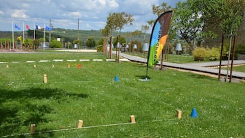 Un campo cubierto de hierba con una bandera, árboles y un sendero.