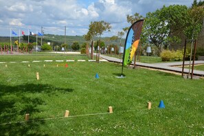 A grassy field with a flag, trees, and a pathway. - Hotel Le Domaine De Baulieu (Auch)