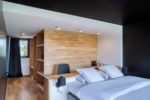 A modern bedroom with a bed, a desk, a chair, and built-in shelving.