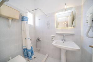A bathroom with a shower, toilet, sink, and a mirror. - Studios Vrionis Panoramic Sunset (Kefalonia)