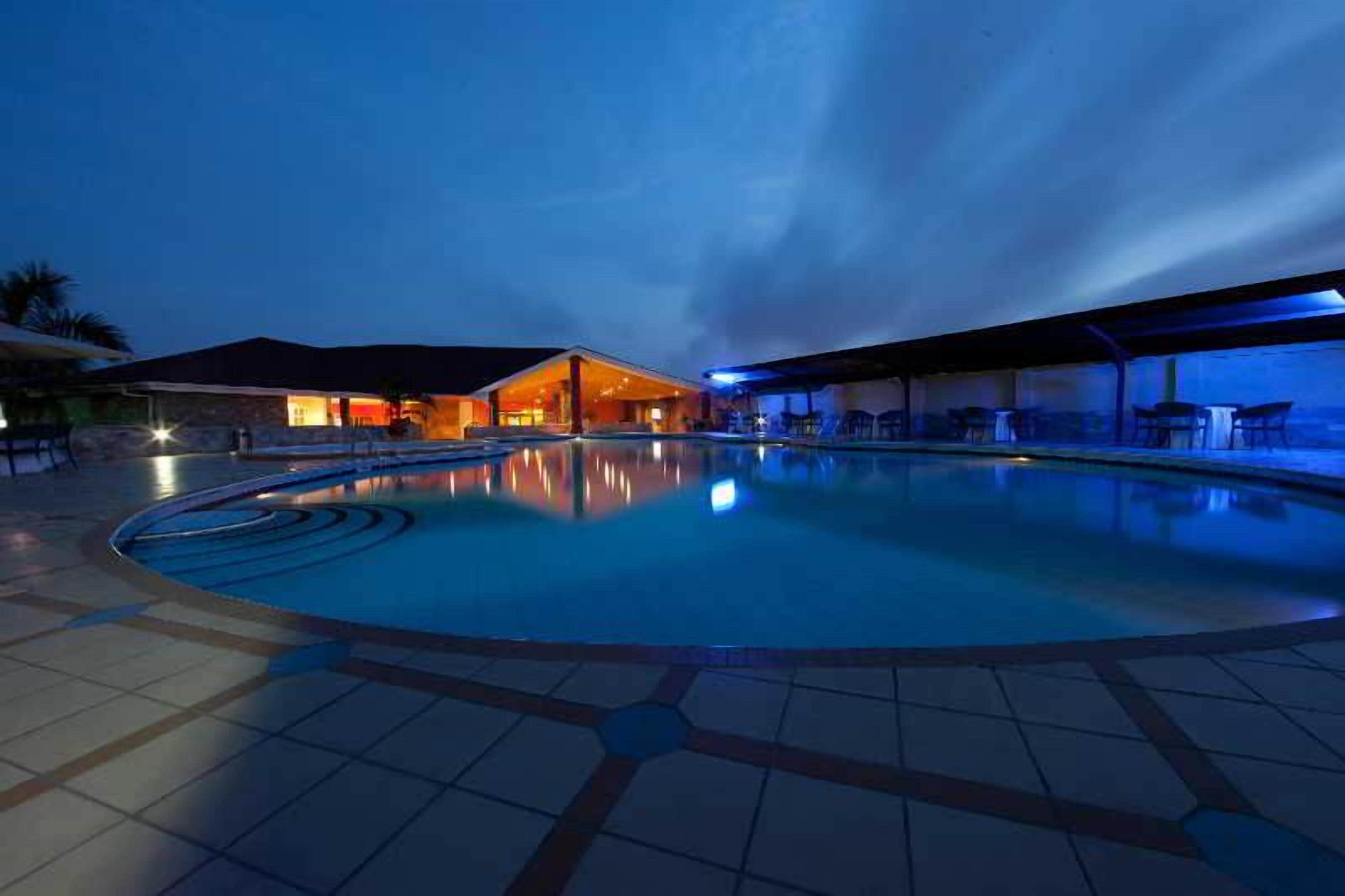 En swimmingpool med ett överbyggt område och en byggnad i bakgrunden.