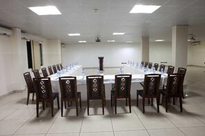 A conference room with a long table, chairs, and a projector screen. - Oak Plaza Hotel East Airport (Accra)