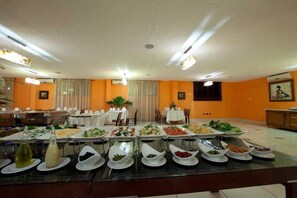 A buffet setup with various food items and a dining area with tables and chairs. - Oak Plaza Hotel East Airport (Accra)