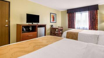 A hotel room with two beds, a desk, a television, and a window with curtains.