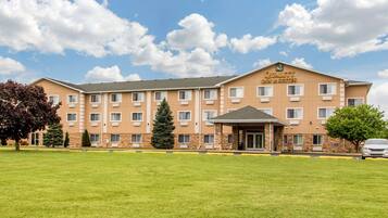 A multi-story hotel with a flat roof, a covered entrance, and a sign reading 'Quality Inn & Suites.'