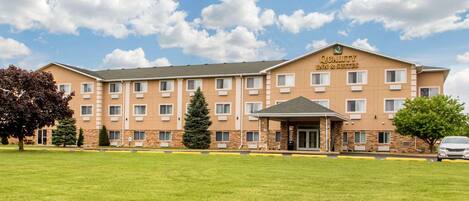 A multi-story hotel with a flat roof, a covered entrance, and a sign reading 'Quality Inn & Suites.'