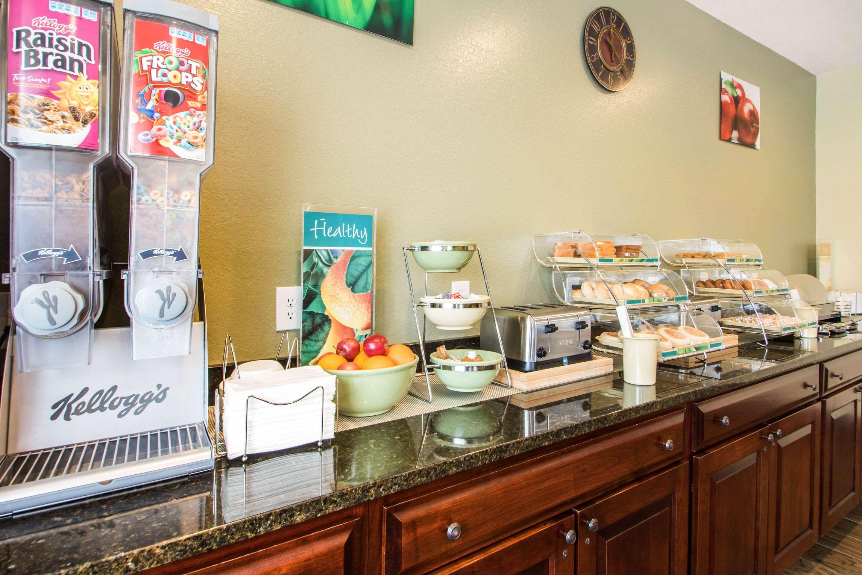 A breakfast buffet with various food items, a clock, and a fruit bowl.