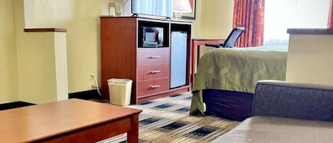 A hotel room with a bed, a desk, a television, a lamp, and a waste bin.