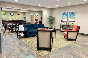 A hotel lobby with a seating area, a reception desk, a clock, and a plant. - Quality Inn & SUI Wisconsin Dells Dwntn-waterparks (Wisconsin Dells)