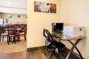 A hotel room with a dining area, a desk with a computer and printer, and artwork on the wall. - Quality Inn & SUI Wisconsin Dells Dwntn-waterparks (Wisconsin Dells)