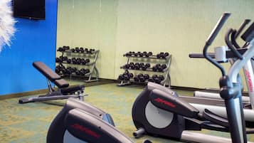 Un gimnasio con equipo de ejercicios, incluyendo cintas de correr y mancuernas.