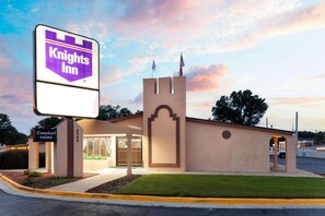 A Knights Inn hotel with a castle-like entrance, a Comfort Rules sign, and a clear sky.