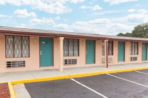 A motel with a row of rooms, each with a green door and a window with a diamond pattern. - Knights Inn Tucker (Atlanta)