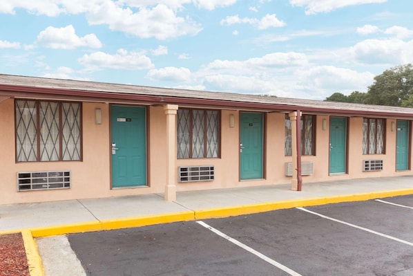 A motel with a row of rooms, each with a green door and a window with a diamond pattern. - Knights Inn Tucker (Atlanta)