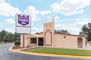 Un Knights Inn con fachada color beige, una torre central y un cartel.