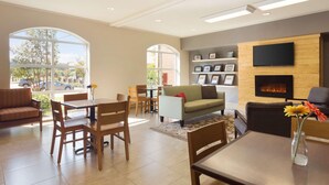 Un hall d’hôtel moderne doté d’une cheminée, d’un espace salon et d’un téléviseur fixé au mur.