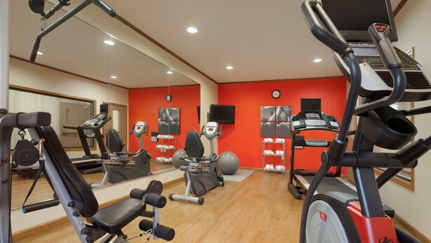 A gym with cardio machines, weight equipment, and mirrors.