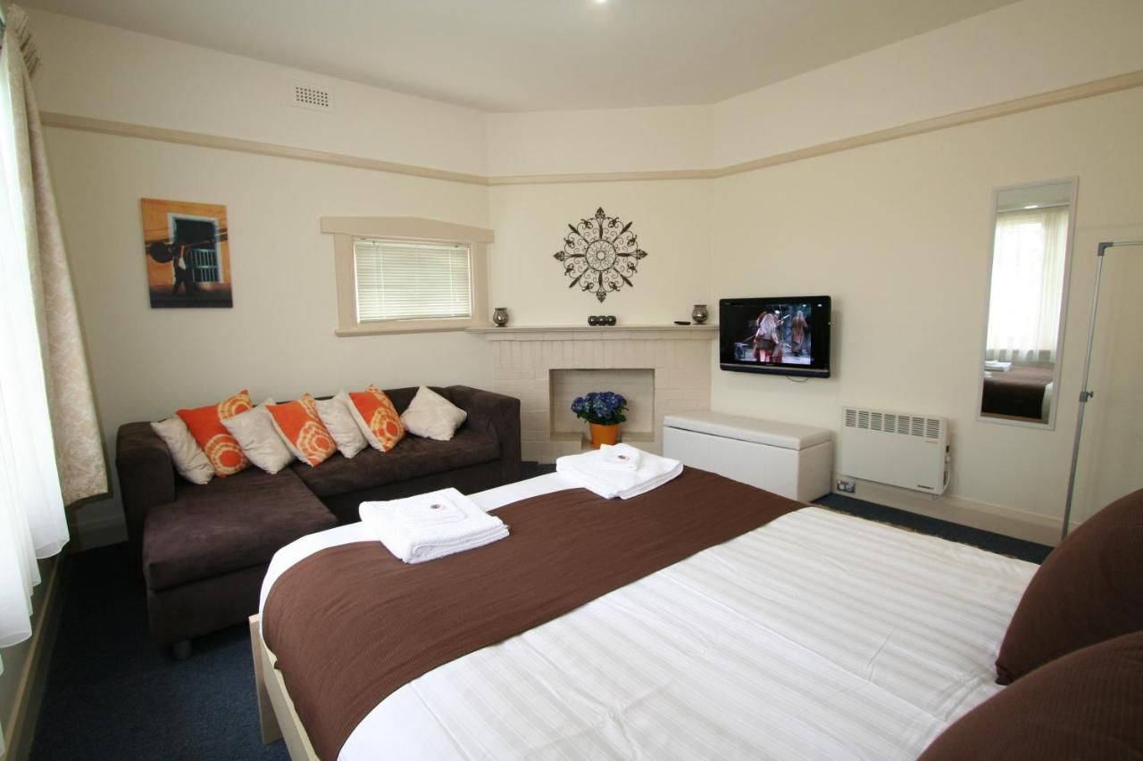 Una habitación de hotel con cama, sofá, televisor, chimenea y ventana.