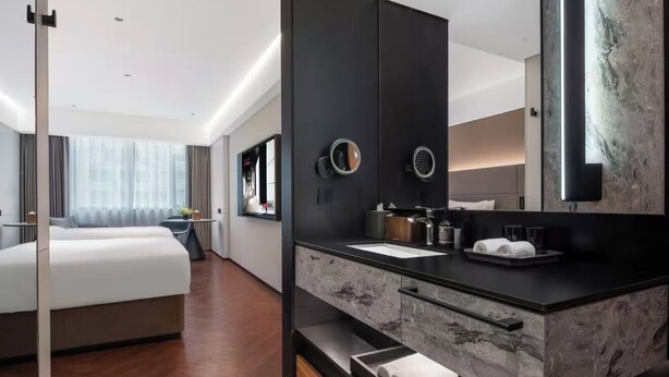 A modern hotel room with a large bed, a dark vanity with a mirror, and a large window with curtains. - Intercity Shanghai South Xizang Road (Shanghai)