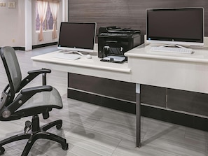 Un escriptori modern amb dos monitors, una impressora i un teclat.