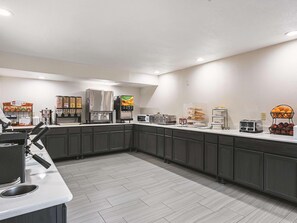 A modern kitchen with a coffee station, microwave, toaster, and a fruit display. - La Quinta Inn & Suites by Wyndham Minneapolis NW (Brooklyn Park)
