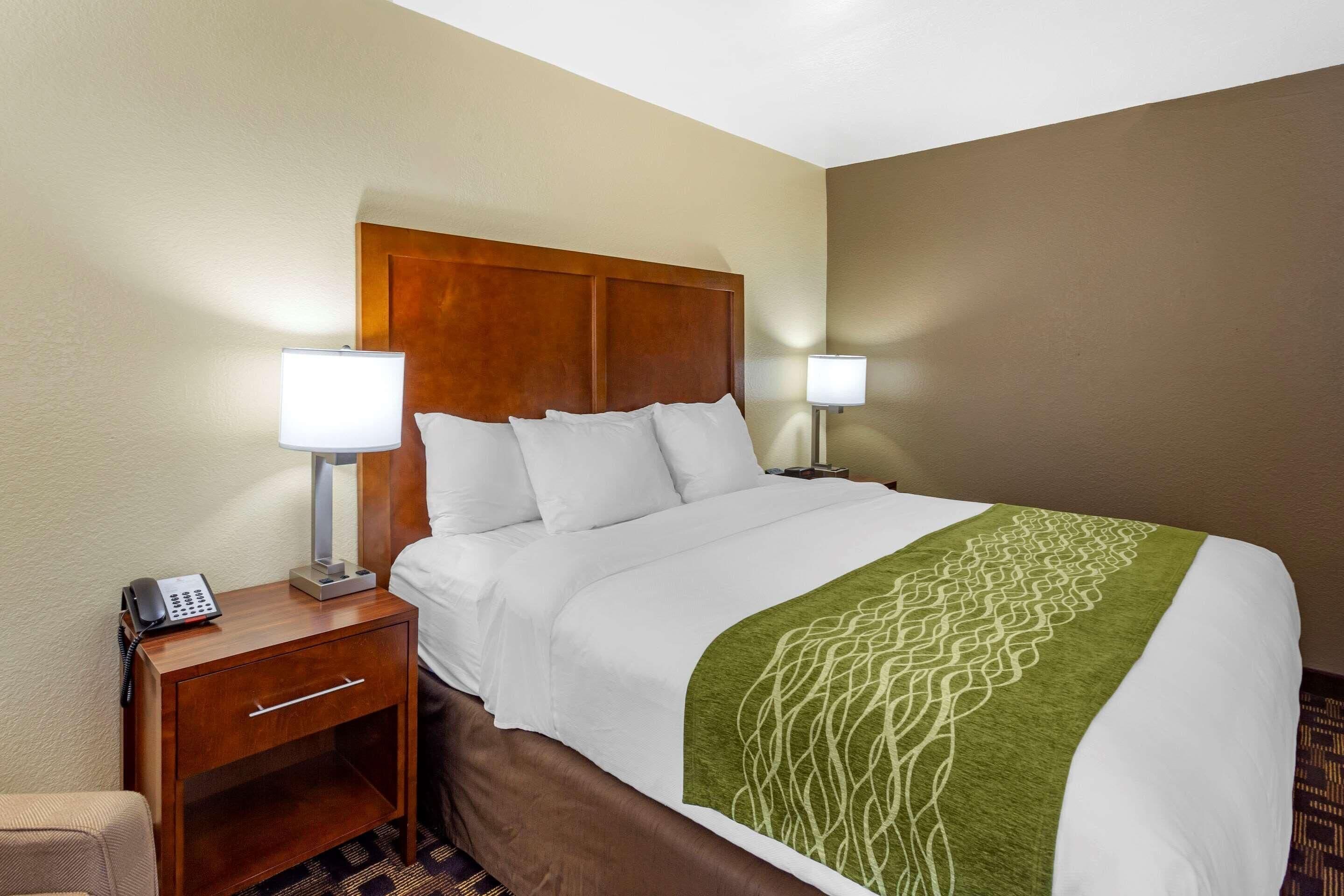 A hotel room with a bed, two bedside tables, a lamp on each table, and a telephone on one table.