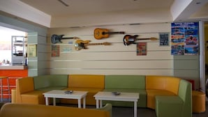 En entréhall med en grön och gul soffa, ett litet bord och gitarrer på väggen.