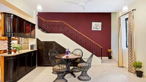 A kitchen with a dining table and chairs, a staircase, and a ceiling fan. - De Mandarin Beach Resort Suites & Villas Goa (Candolim)